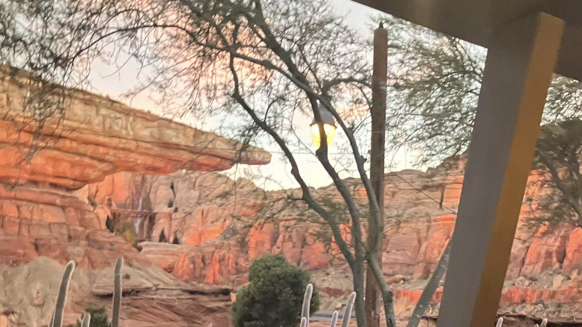 View of Radiator Springs Racers attraction from patio of Flo's V8 Cafe. Trees and rockwork of Cars Land in Disney California Adventure Park.