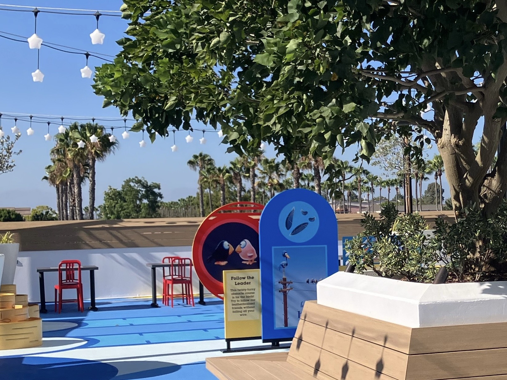 View of the Pixar Shorts Court showing some of our favorite features including Bao Toss, La Luna lights, For the Birds sign and landscaping.