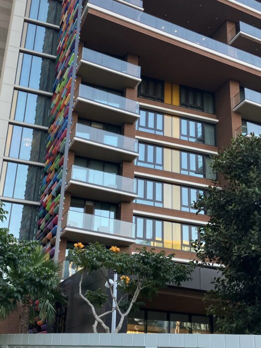 Exterior view of guest room tower for Disneyland Hotel DVC Villas. Shows landscaping around colorful building with shiny windows and balconies.