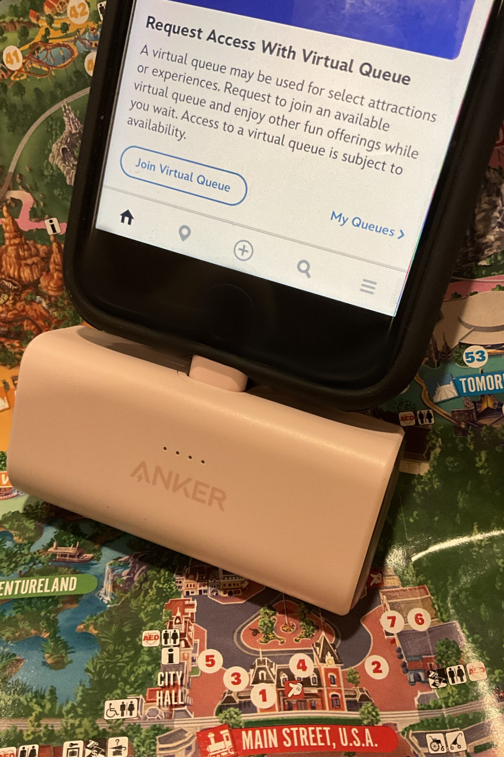 Anker Nano Power Bank on Disneyland Park map next to logo for Play Disney Parks mobile app. Illustration of importance of using a portable charger back-up battery while visiting Disneyland Park and Disney California Adventure Park.