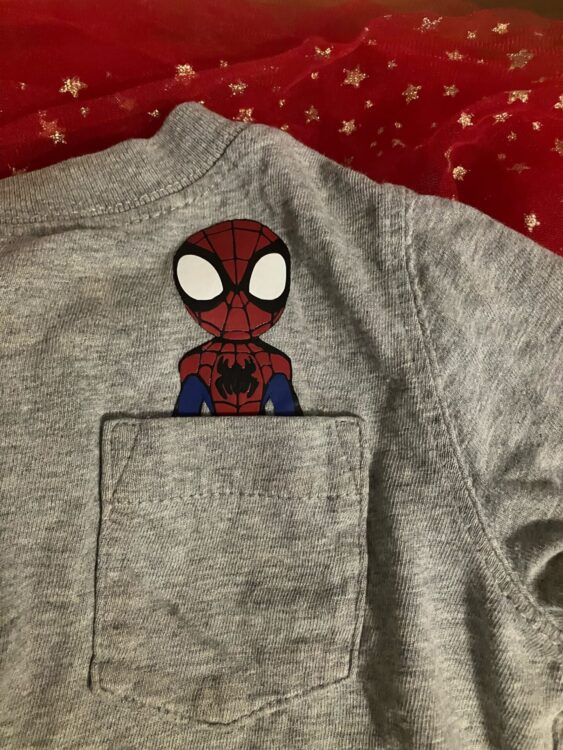 Spidey iron-on vinyl appliqué placed on child’s tee showing him poking out of pocket.