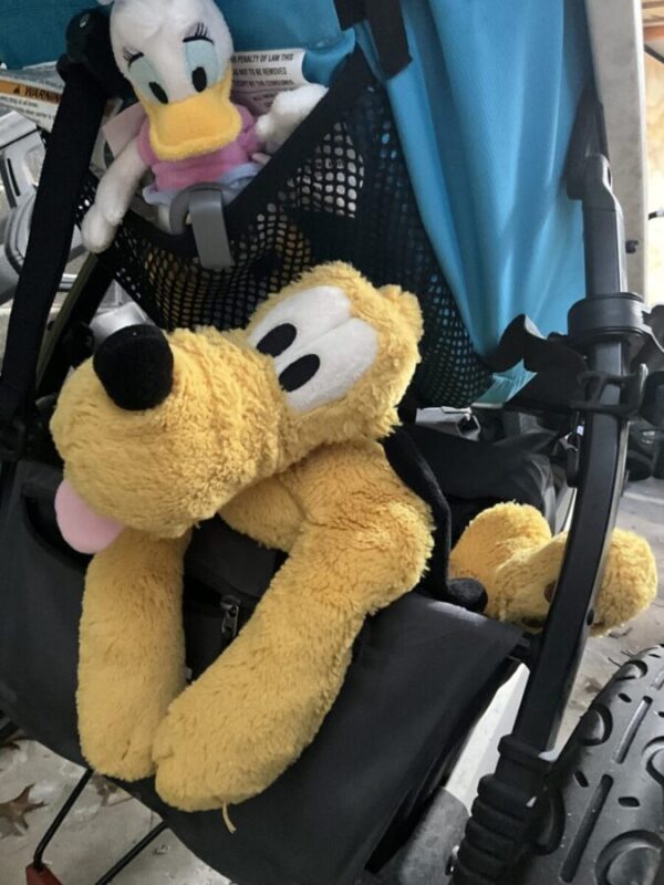 Apple AirTag clipped to stroller pocket to use in Disneyland. Image shows teal stroller with Apple Air Tag, Daisy and Pluto for Disneyland Visit.