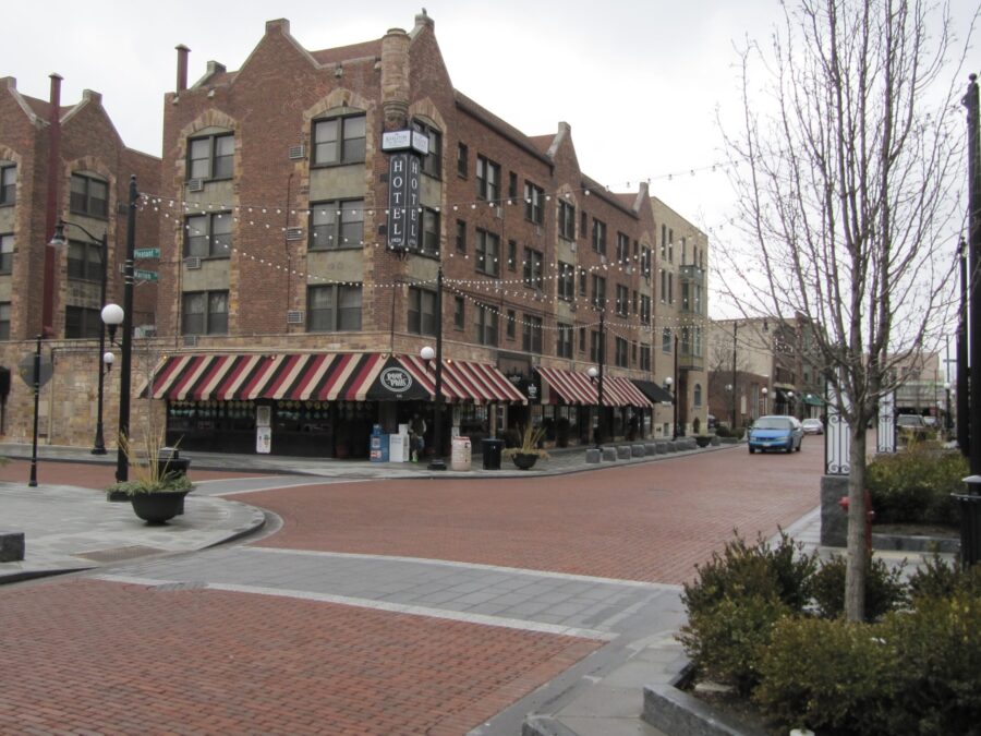 View north on Marion Street in Oak Park, Illinois showing brick paved street, planter boxes and a brick structure with awning that is the Carleton hotel and Poor Phils restaurant and bar. String lights are starched over the street.