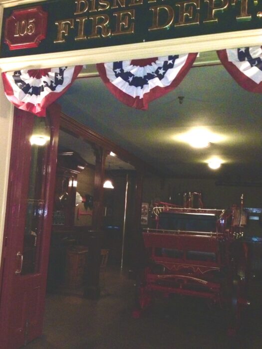 Photo of the inside of Disneyland Fire Department taken at night. Shows bunting, lights and firetruck.